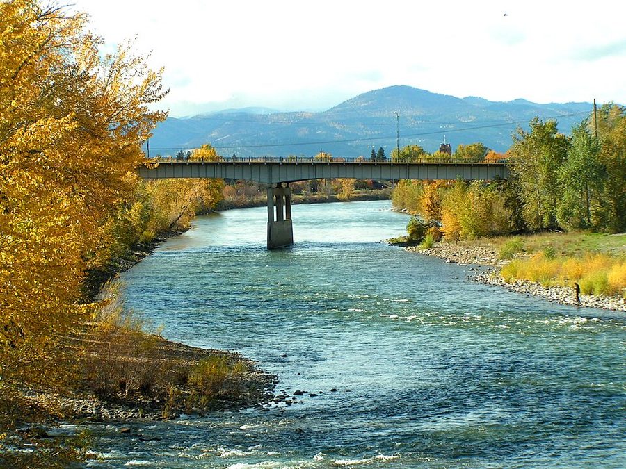 The Clark Fork river in autumn, running between forested hills.