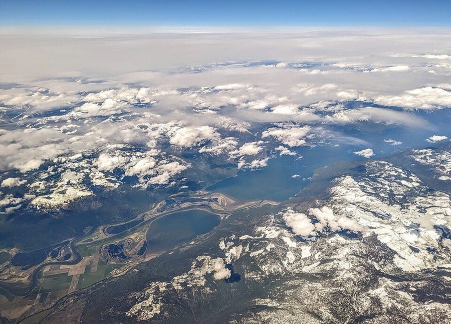 Kootenay Lake and Duck Lake from the air near Creston, British Columbia — flat farmland giving way to a long blue lake between mountains.