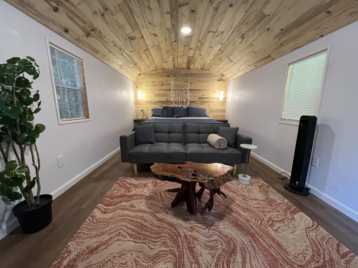Inside a cabin at Round Mountain Retreat — wood-panelled ceiling, modern furnishings and a view into the forest.