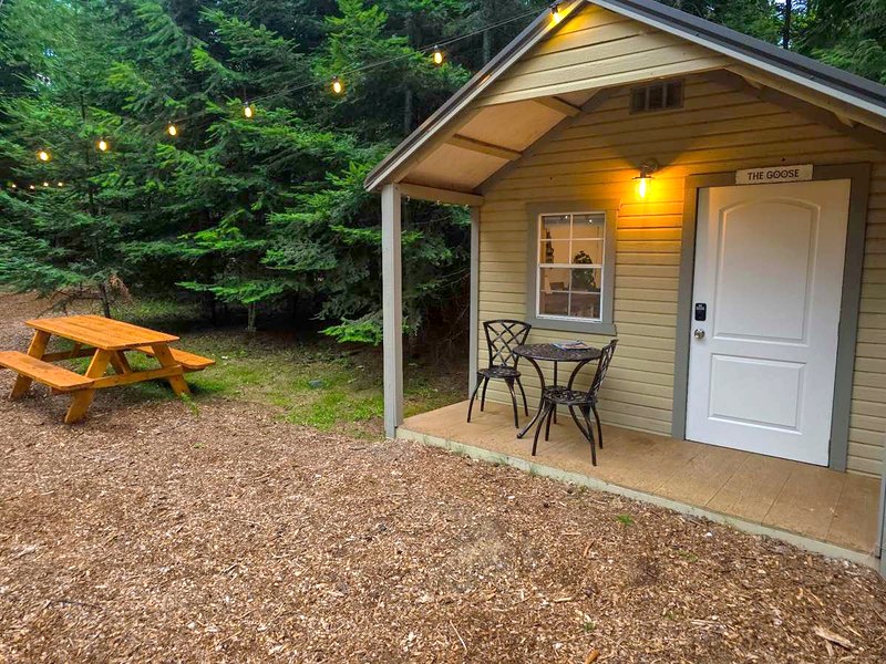 The Goose cabin porch at dusk, with a picnic table and string lights overhead.